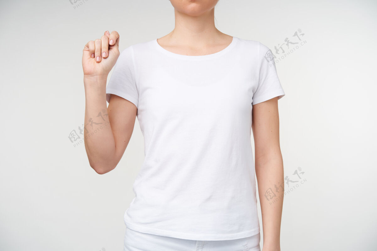 站立室内拍摄的年轻女子举起手紧握着它 同时展示了死亡字母表中的字母t 站在白色背景下手女人女性