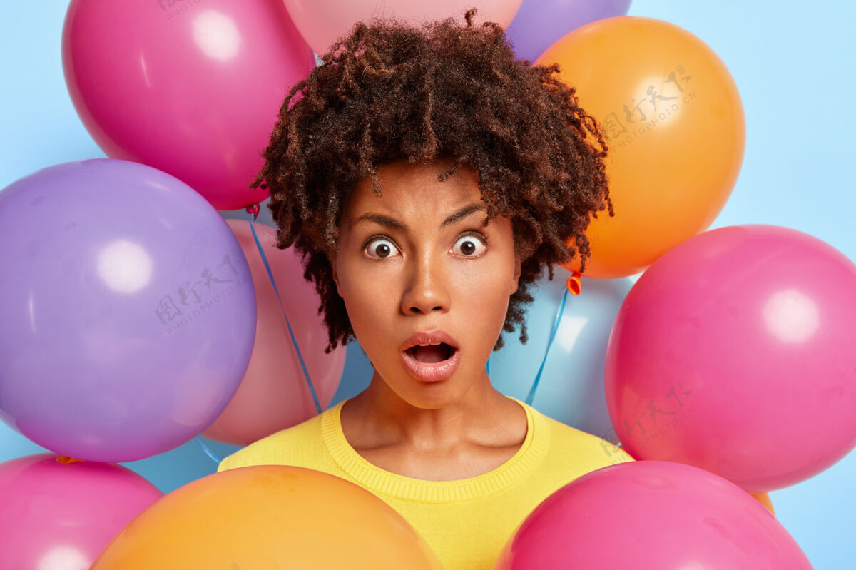 印象摄影棚的肖像 惊讶的年轻女子摆姿势周围的生日彩色气球生日惊人女人