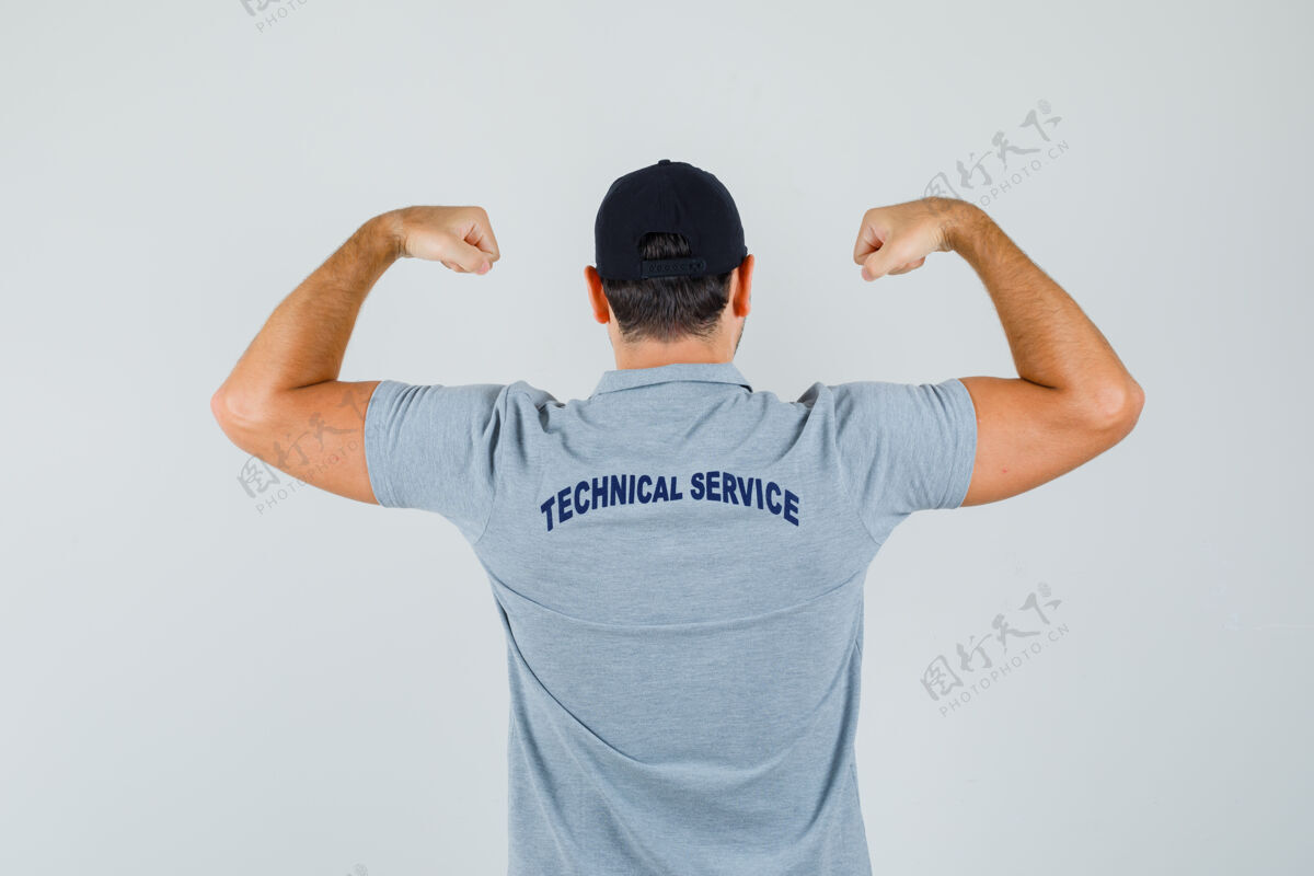 维护年轻的技师穿着灰色制服展示手臂肌肉 看上去很有力后视图车间技术人员背部