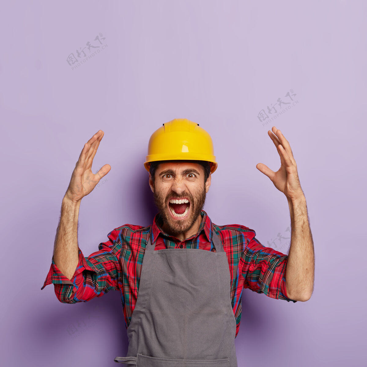 紫色恼怒的情绪化工人戴着黄色的建筑防护头盔 格子衬衫和围裙 有很多工作要做 带着压力和恐慌尖叫 情绪化地举起手臂机械围裙修理