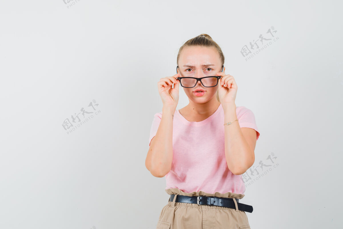 成人金发女孩穿着t恤 裤子 正对着眼镜聚精会神地看着可爱看人