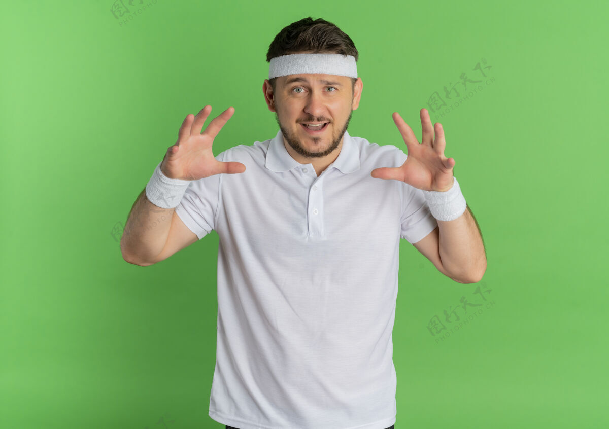 爪子身穿白衬衫 头上戴着头巾的年轻健身男子像猫一样做爪子动作 微笑着站在绿色的背景上站立绿色微笑