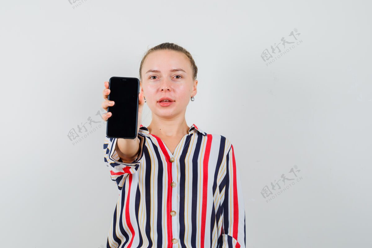 秀一个穿着条纹衬衫的年轻女人在展示她的手机 看上去很乐观女性成人休闲