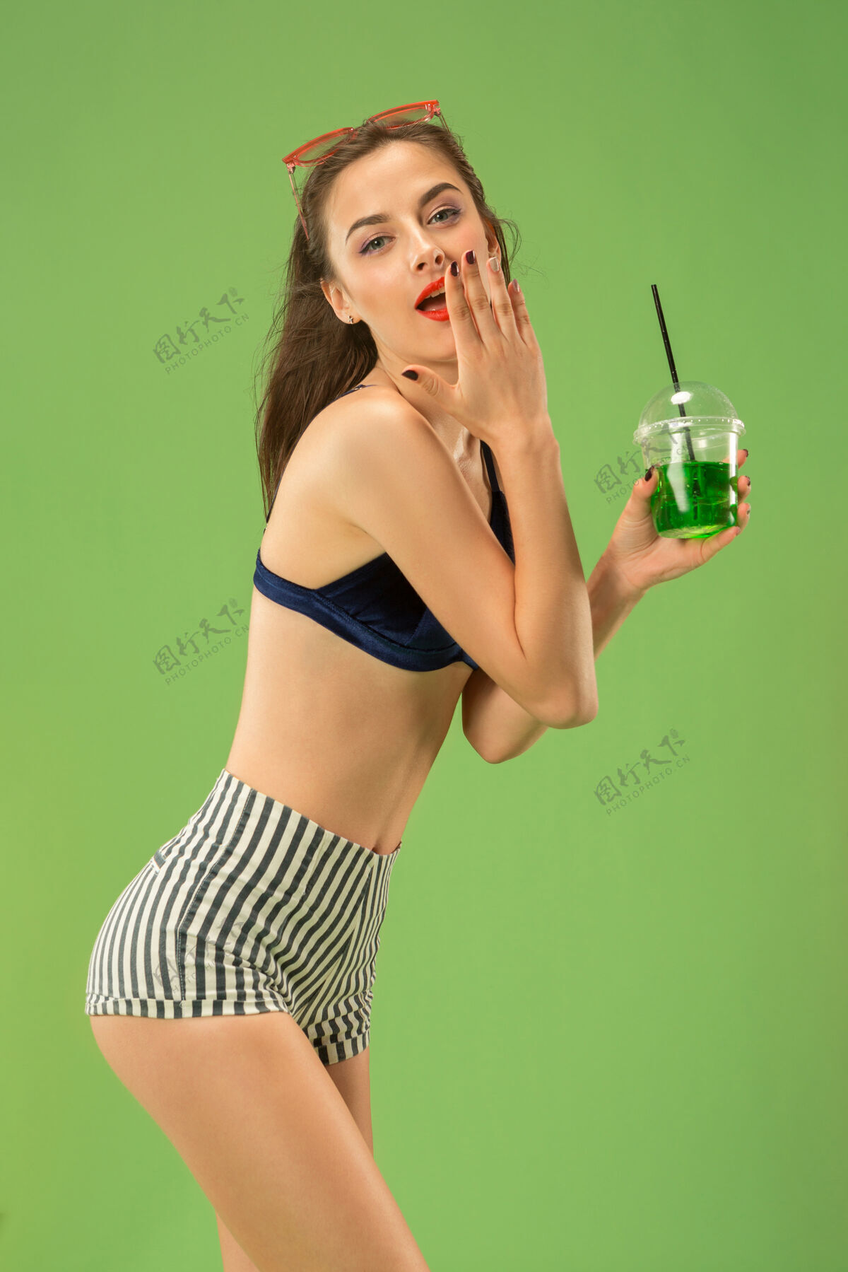 美丽穿着泳装的可爱女孩在摄影棚摆姿势绿色背景上的夏日白种人少年肖像欢呼年轻微笑