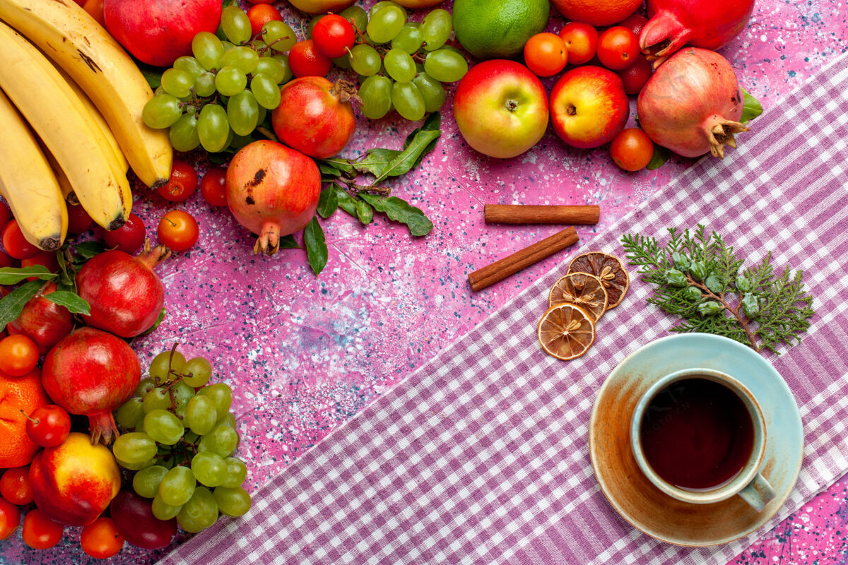 多汁顶视图新鲜水果组成五颜六色的水果与茶和肉桂杯粉红色的表面茶食物肉桂