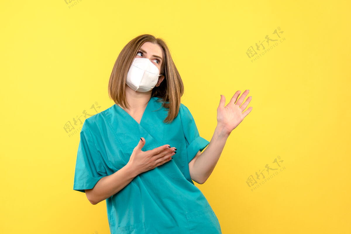 女士黄色空间上戴面罩的女医生的正面图肖像人医院