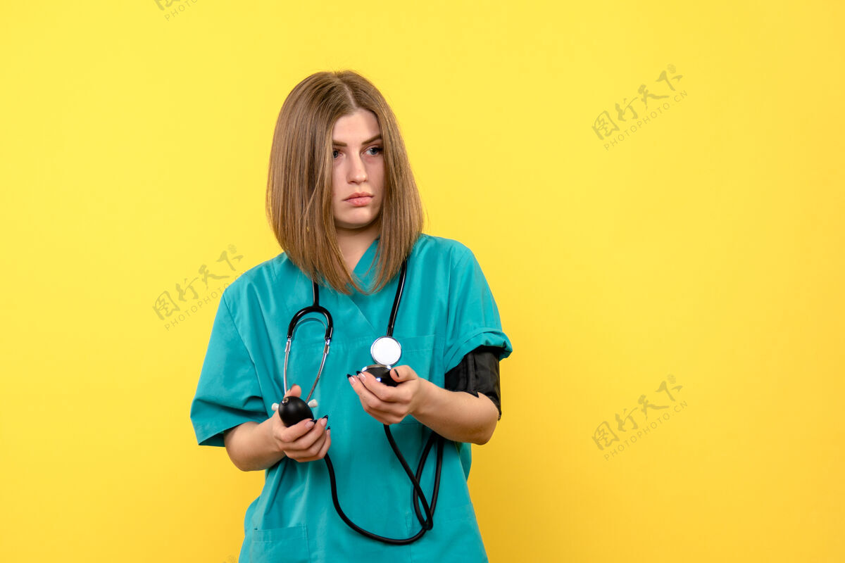 药品前视图女性医生在黄色空间使用眼压计仪器黄色血压计