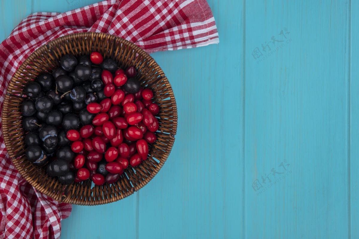 空间顶视图的水果 如山茱萸和树莓在篮子上的格子布蓝色背景与复制空间树莓蓝色食物