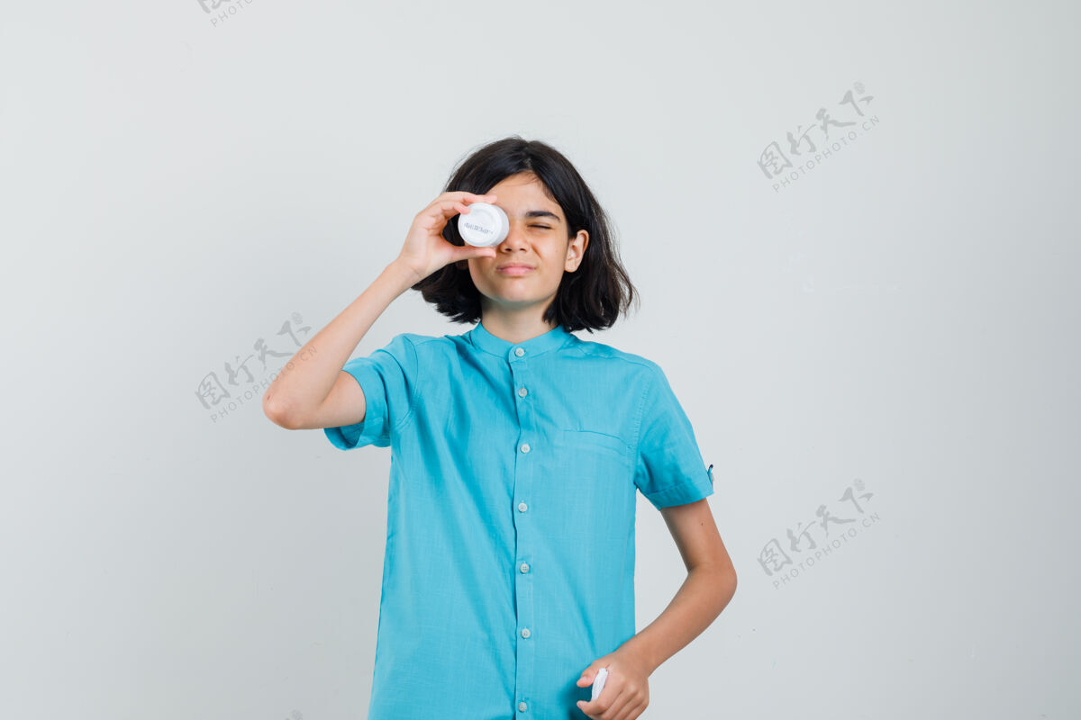 欢呼穿蓝衬衫的年轻女士拿着一瓶药片遮住眼睛 看上去很滑稽时尚积极女士