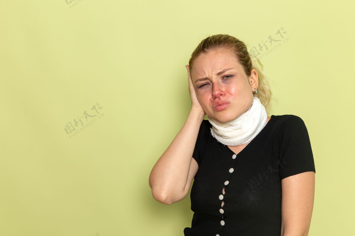 疾病正面图年轻女子用白毛巾捂住喉咙 感觉很不舒服 病在浅绿色墙上病得很不舒服 病得很不舒服视图支架加强