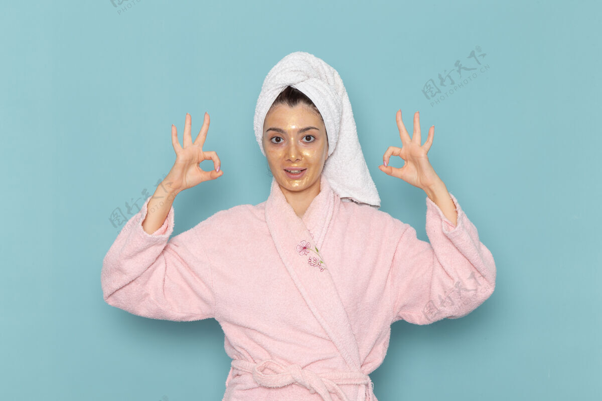 自理正面图身着粉色浴袍的年轻女性在蓝色墙壁上淋浴后清洁美丽干净的水自我护理霜淋浴清洁成人人