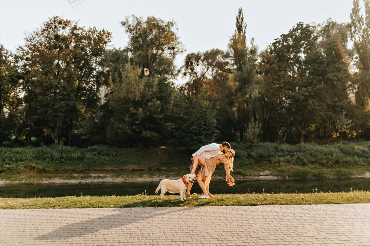 狗夫妻俩在池塘边的公园里玩 跳探戈 和拉布拉多一起散步成人女性微笑