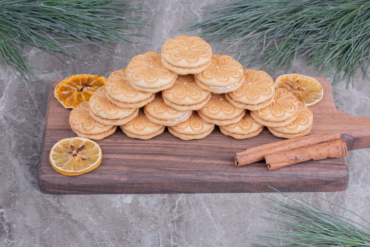 面粉用肉桂棒和干柠檬片放在木板上的饼干圣诞节极简饼干