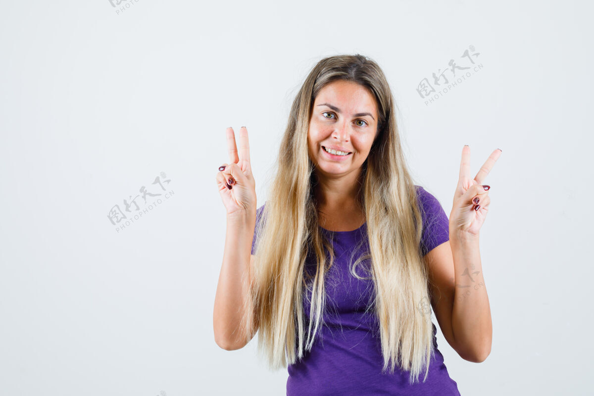 长身着紫罗兰色t恤的金发女士 展现胜利姿态 看起来很快乐 正面视图肖像美丽人