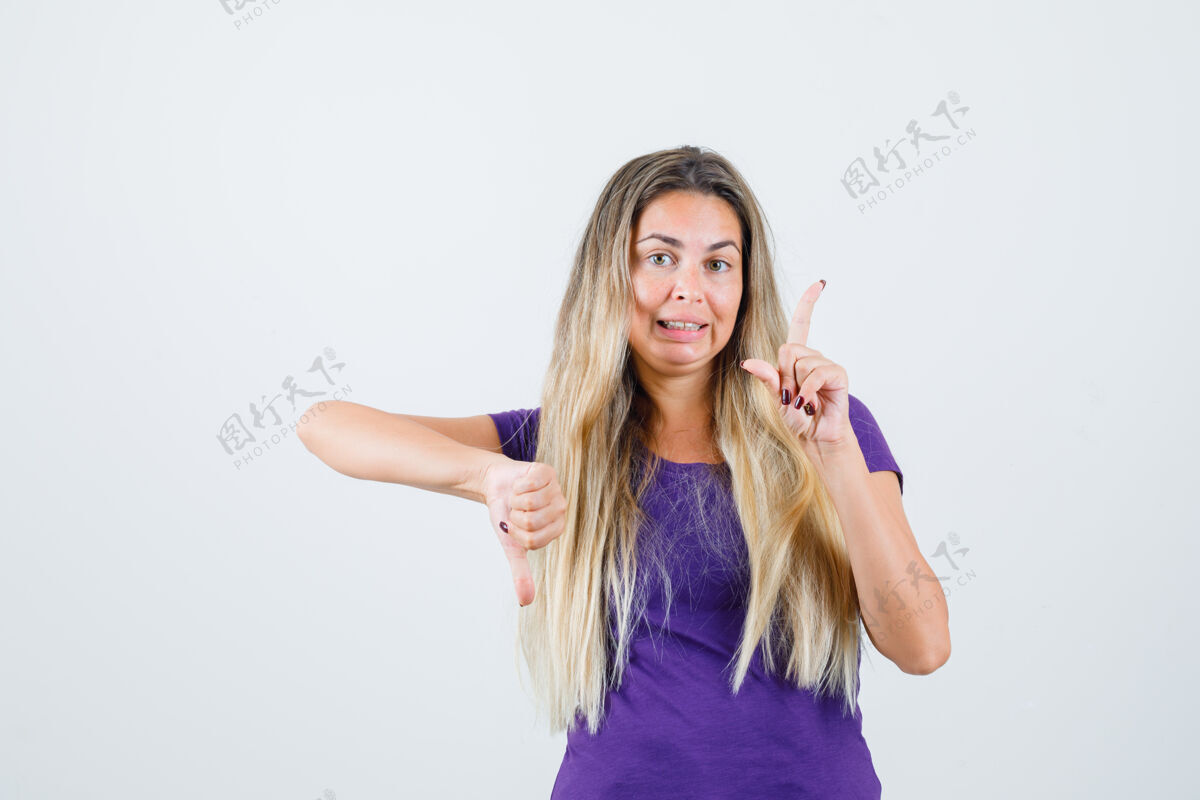 拇指金发女孩拇指朝下 指着紫罗兰色t恤衫 正视图时尚金发可爱