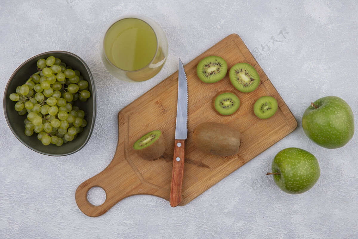 碗顶视图猕猴桃切片与一个绿色的苹果和葡萄在一个碗与苹果汁在一个白色的背景玻璃刀白色果汁猕猴桃