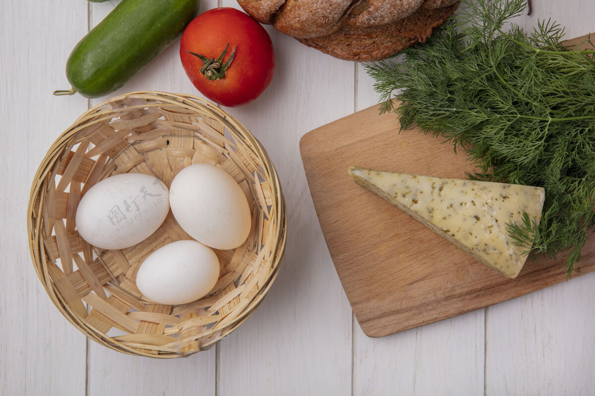 奶酪顶视图鸡蛋在一个篮子里 西红柿黄瓜和一条黑面包 奶酪和莳萝放在白色背景上面包食物营养