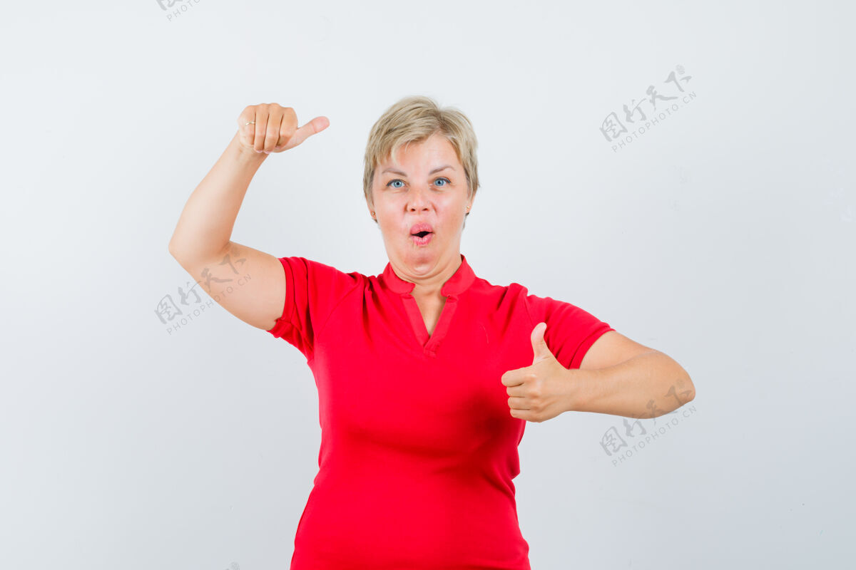 举行成熟的女人竖起大拇指 穿着红色t恤假装拿着什么东西信心姿势女性