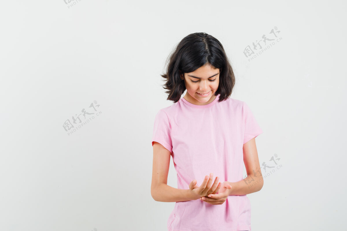 人物小女孩穿着粉色t恤看着她的手掌 看起来很快乐前视图肖像漂亮可爱