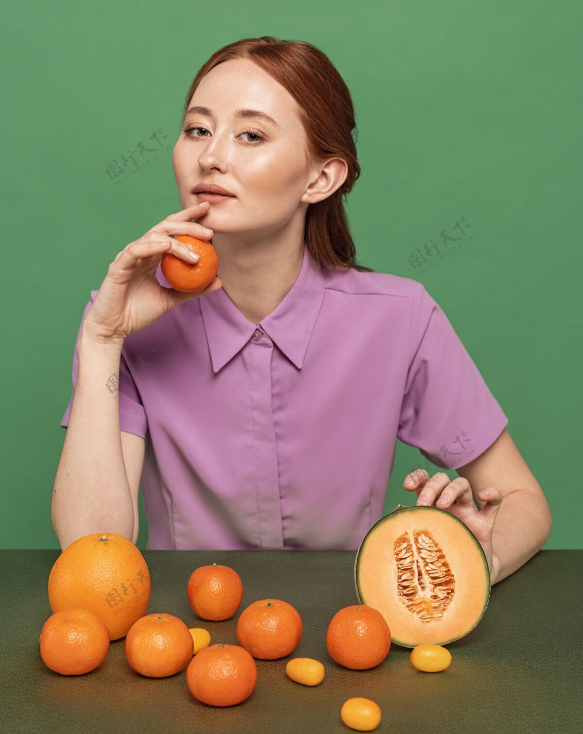 吃美丽的红发女人摆着橘子的姿势美味姿势安排