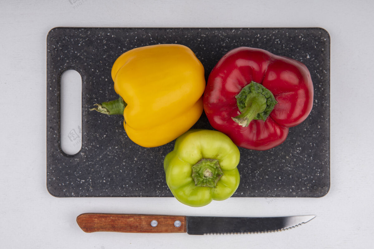 绿顶视图彩色甜椒黄绿色和红色的切菜板上用刀在白色的背景胡椒食物蔬菜