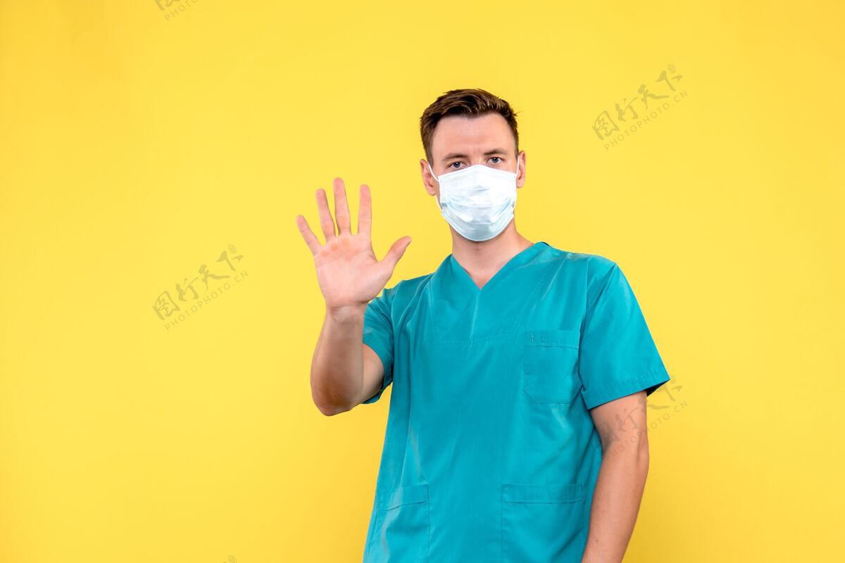 前面男性医生在黄色墙壁上展示手掌的正面视图男性帅哥手掌