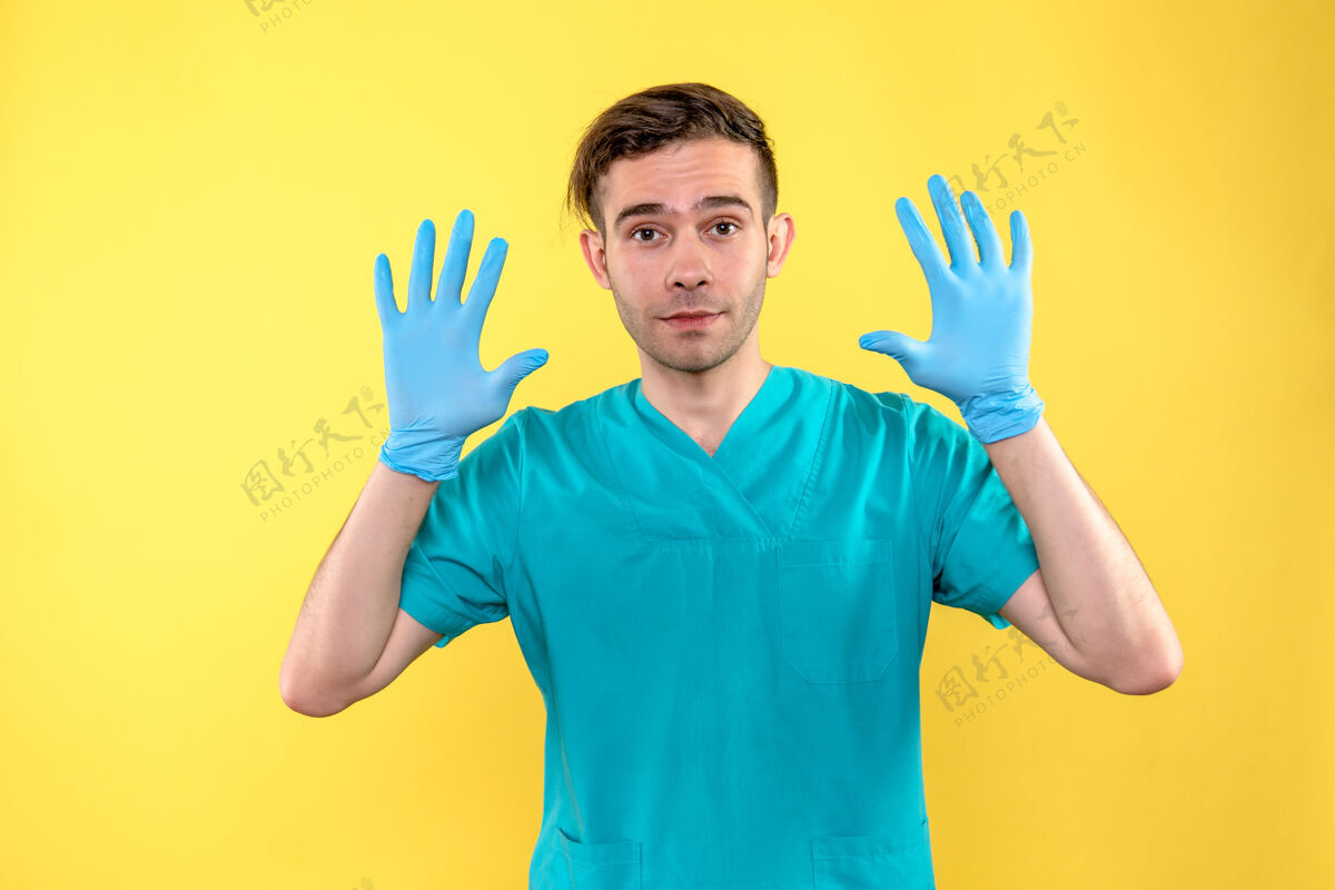 医疗黄墙上戴着蓝手套的男医生的正视图正面手套手