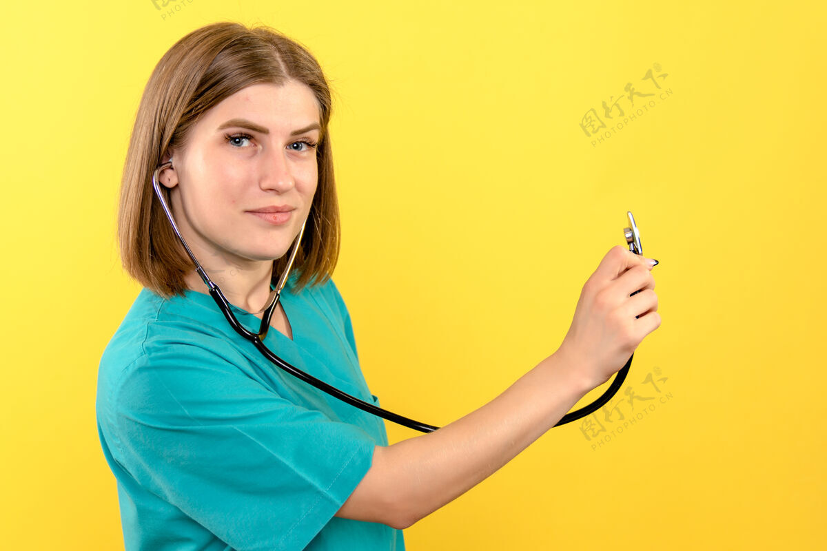 漂亮黄色墙上带眼压计的女医生的正视图医学快乐肖像