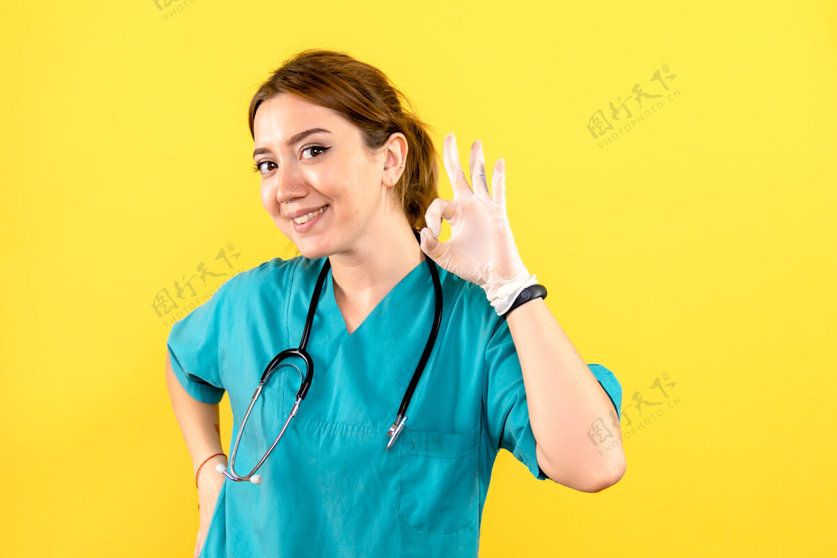 护理黄色墙壁上的女兽医摆姿势微笑的正面图护士药人