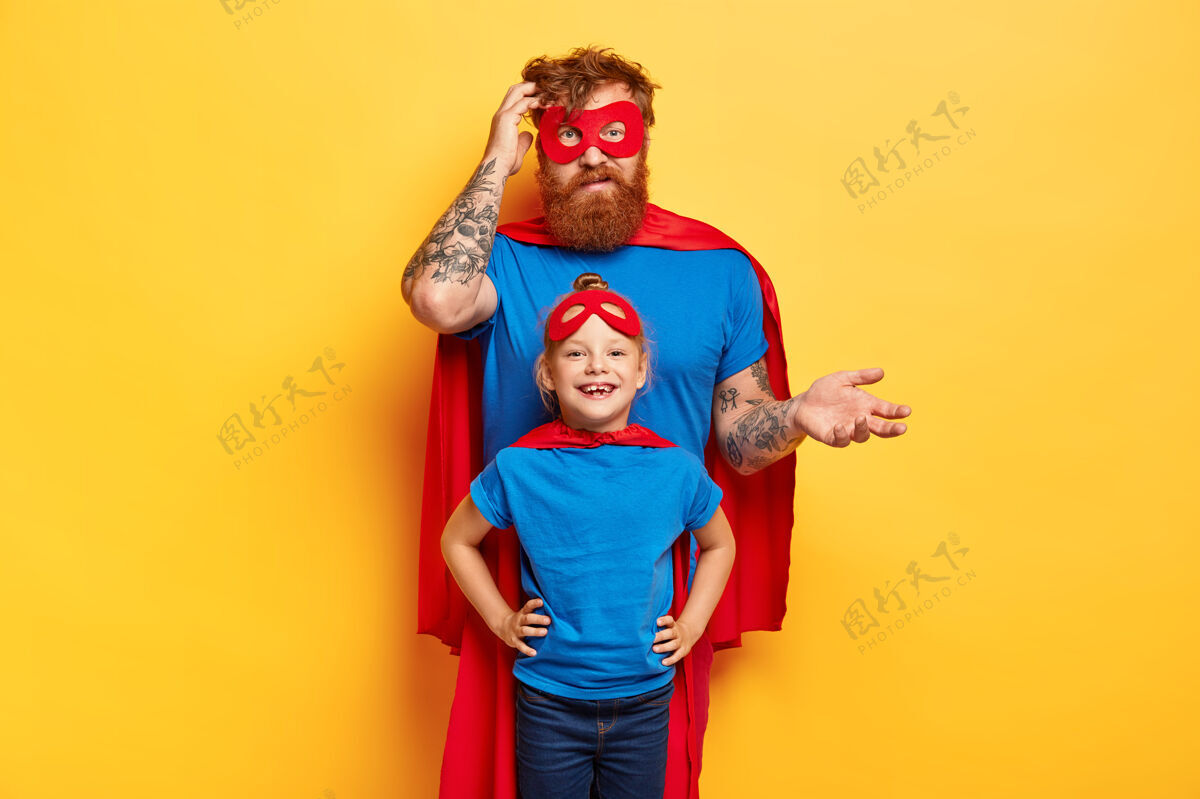 携带顽皮的爸爸带着小女儿穿上超级英雄的服装 在家里一起玩面具休闲纹身