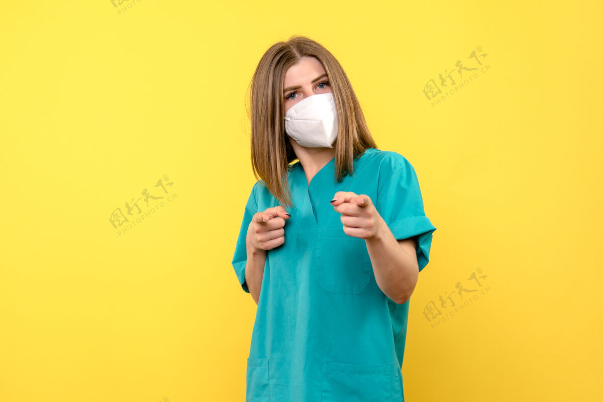 流行病黄色墙上戴着面具的女医生的正面图正面医学成人
