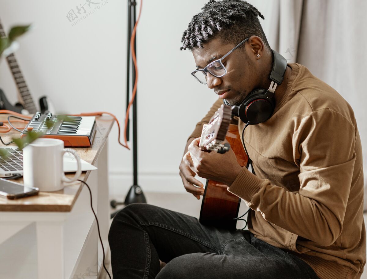 水平严肃的男音乐家在家里弹吉他和笔记本电脑创意乐器手吉他
