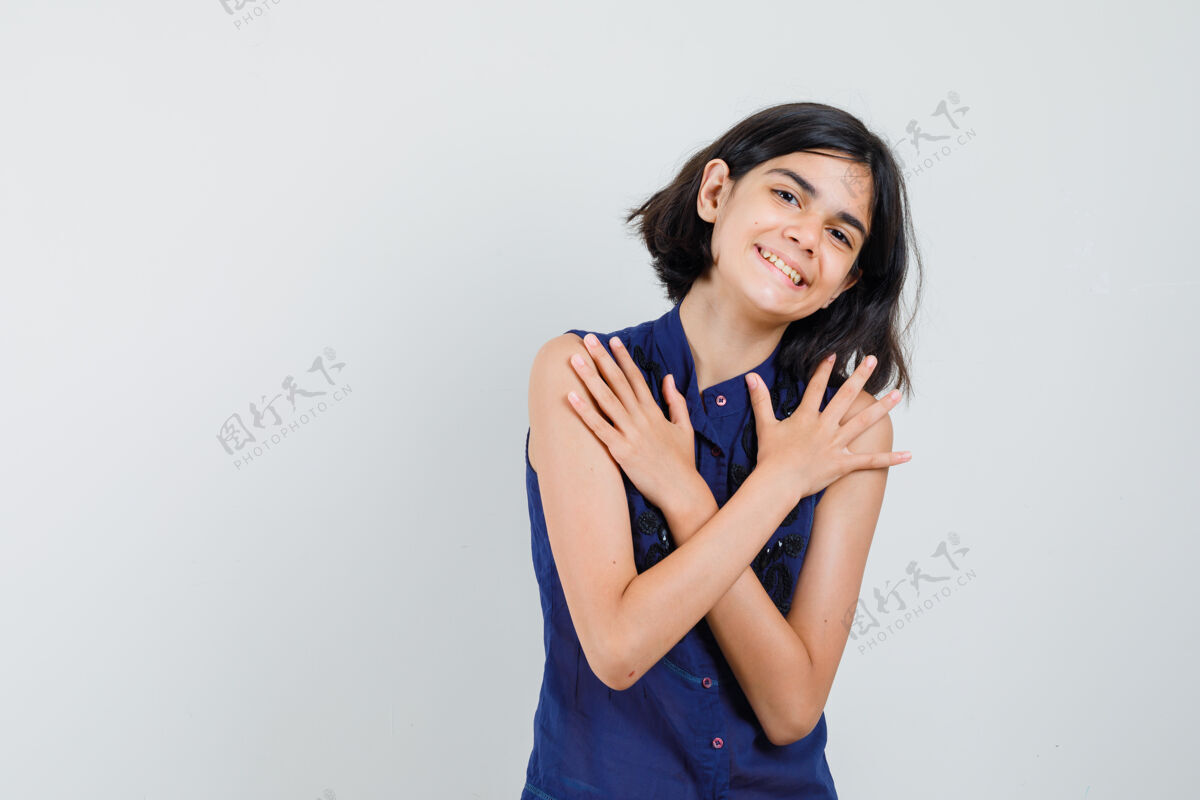 年轻小女孩抱着双臂交叉在蓝色上衣 看起来很快乐前视图休闲积极快乐