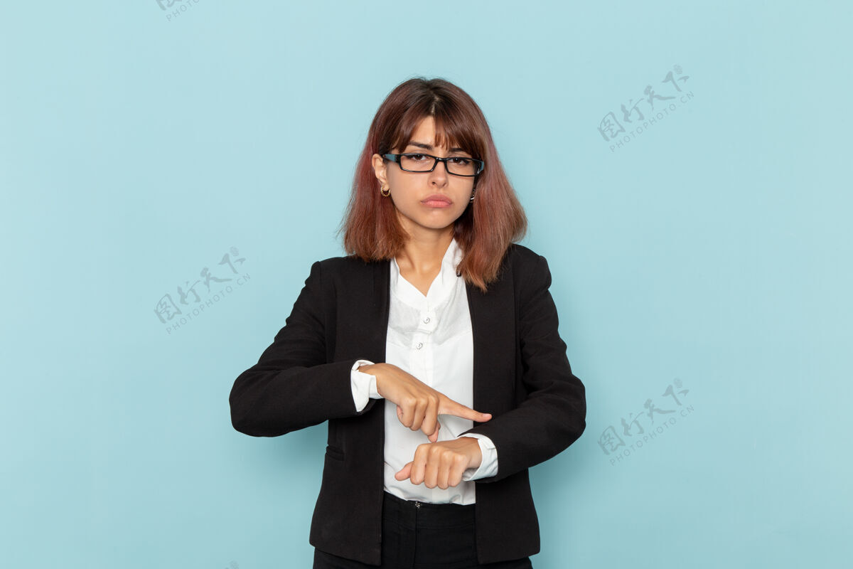 西装正面图：女上班族在蓝色的表面上指着自己的手腕办公室忙工人