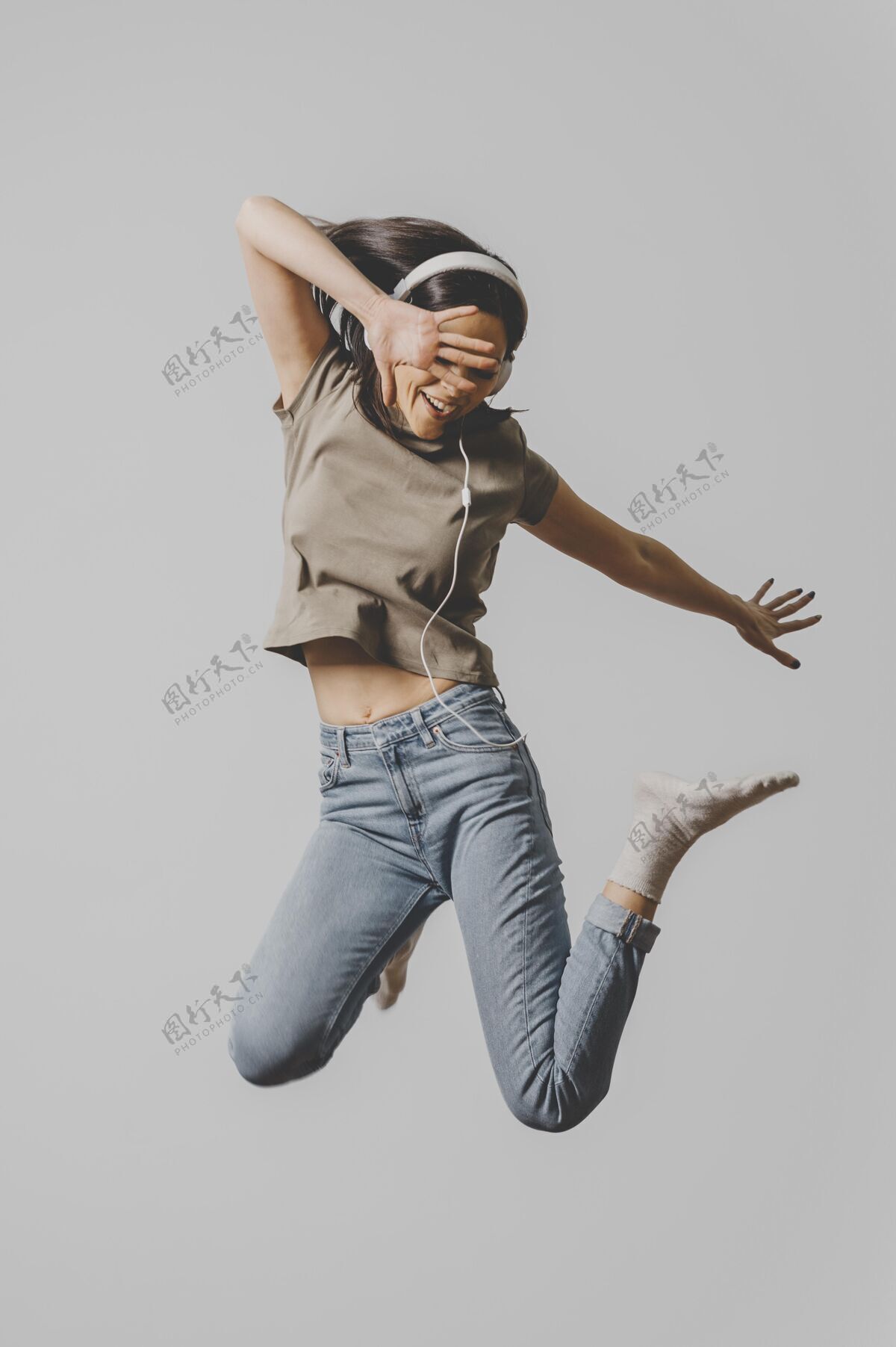 姿势戴着耳机在空中跳跃的快乐女人跳跃快乐跳跃