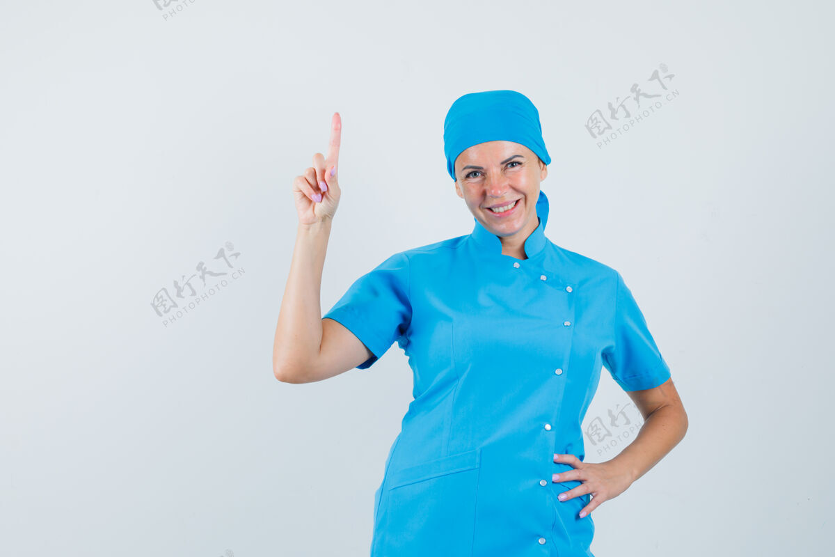 站立女医生指着蓝色制服 看起来很高兴 正面视图治疗工作人员肖像