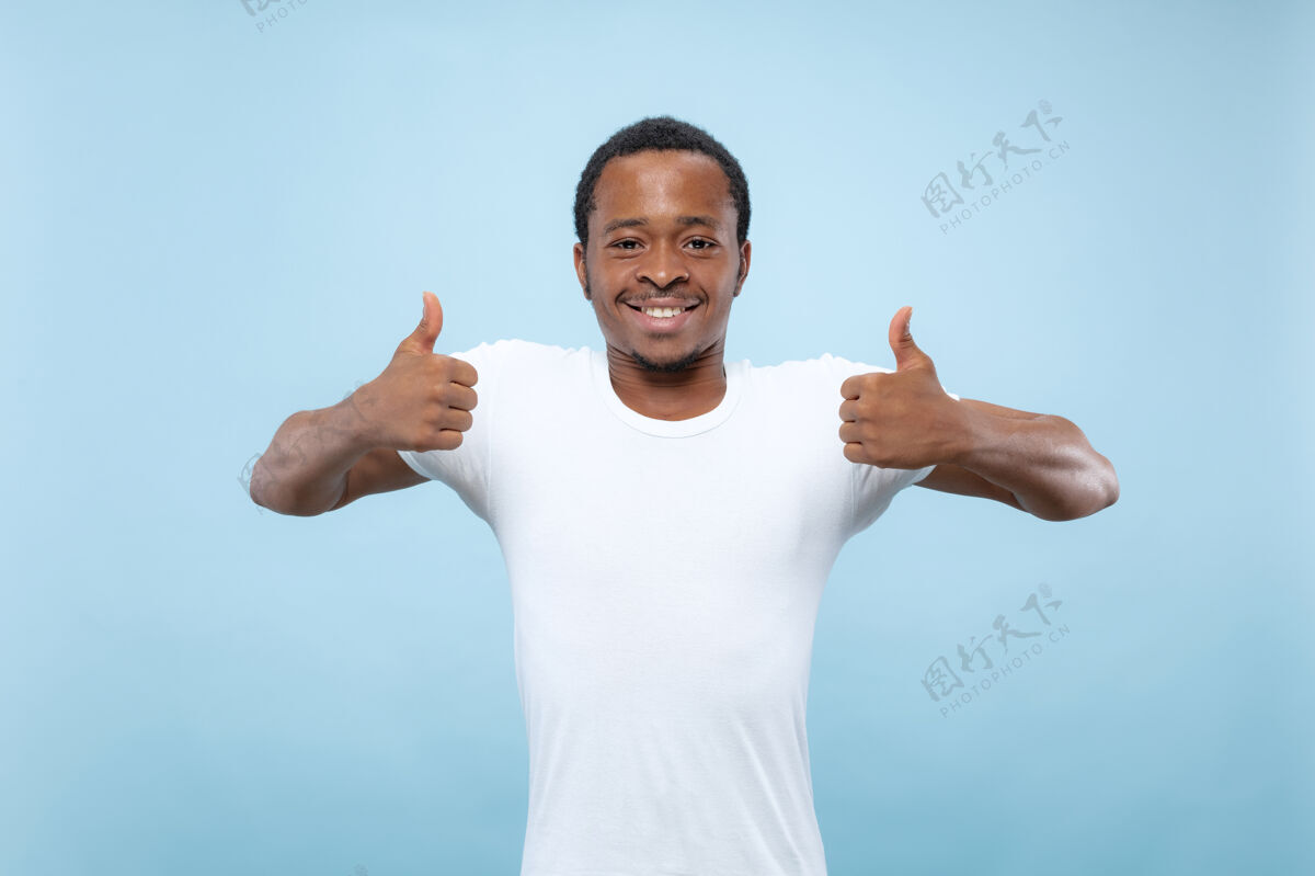 公司在蓝色工作室背景上 年轻的非洲裔美国男模身穿白衬衫的半身特写肖像人类情感 面部表情 广告概念显示ok的标志很好面部专业长相