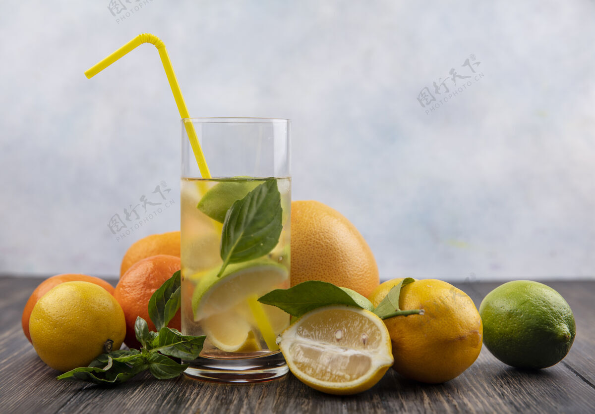 水一杯水 柠檬片 柠檬片 薄荷片 黄色稻草 柚子片 橘子片 木质背景葡萄柚切片前面