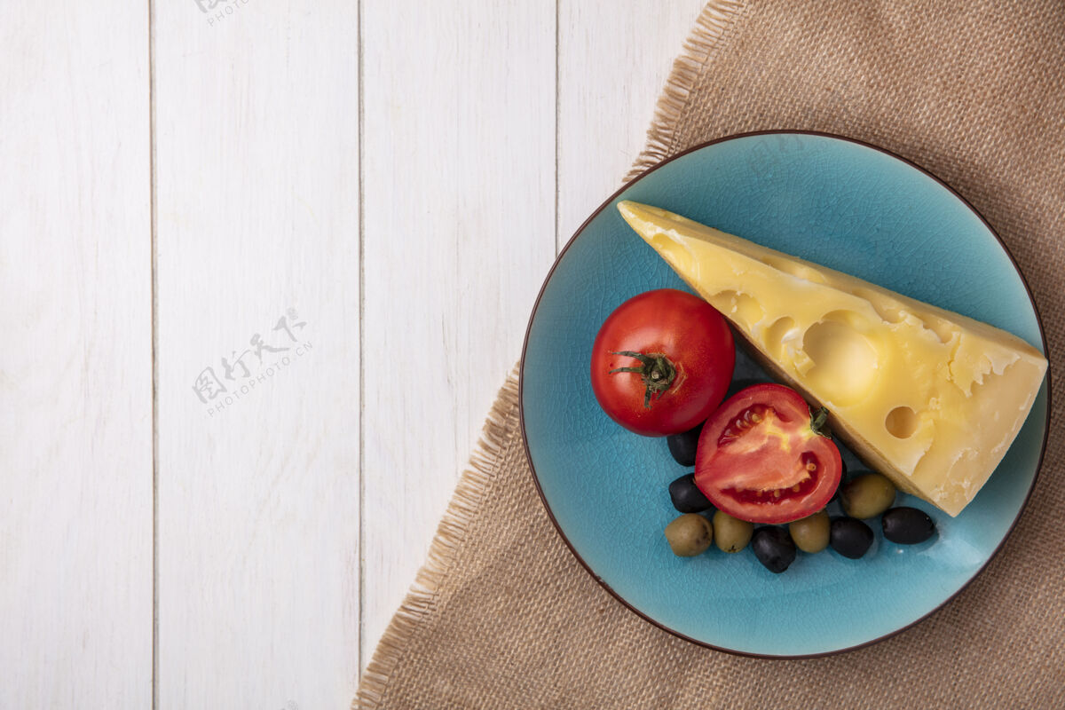 奶酪顶视图复制空间马斯丹奶酪与西红柿和橄榄在一个蓝色的盘子上米色餐巾白色背景米色蓝色盘子