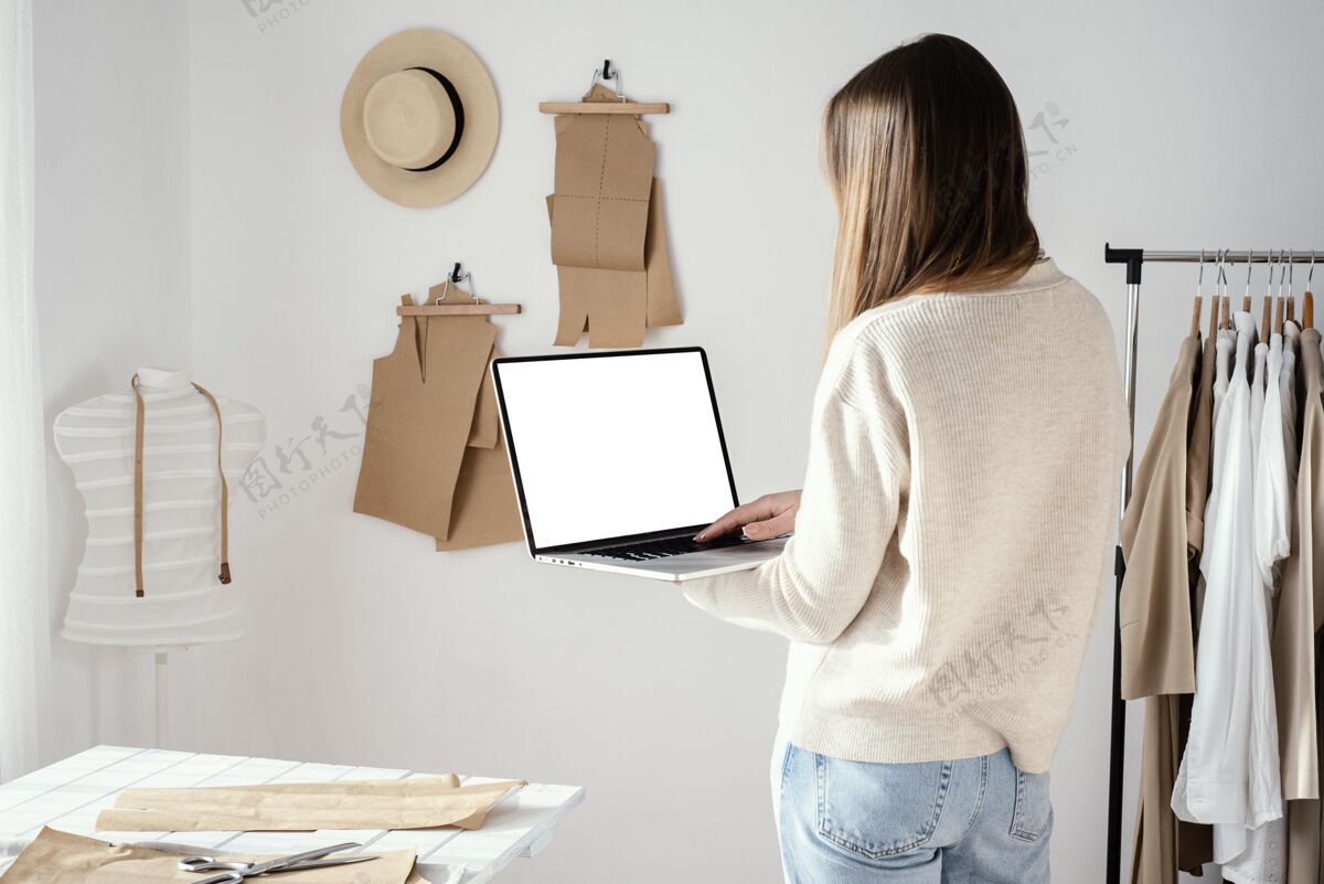 女女裁缝在工作室使用笔记本电脑的后视图裁缝服装针线