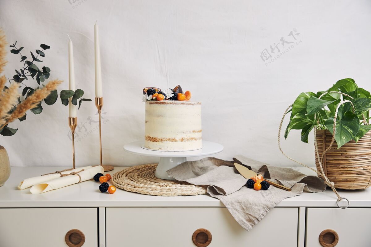 食物白色蛋糕上有浆果和西番莲 旁边有植物和蜡烛烘焙糕点蛋白酥皮