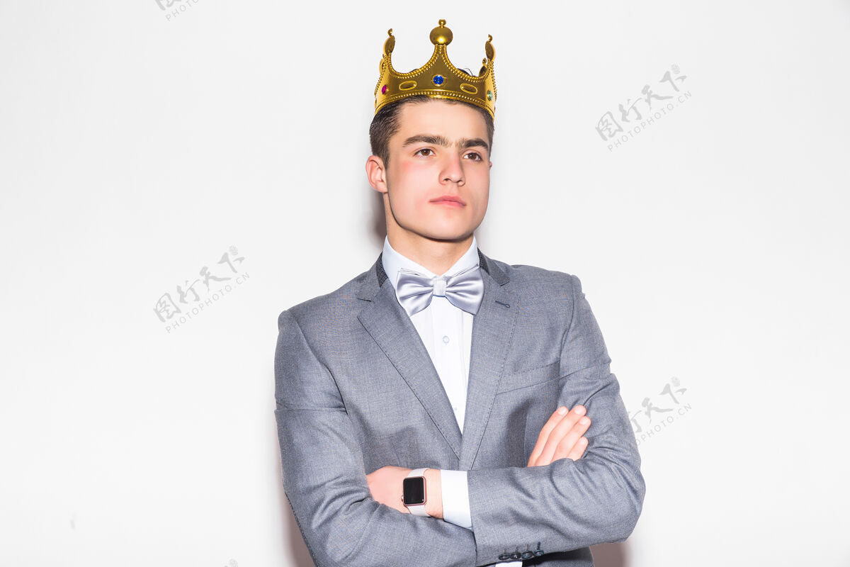 人物一个穿着西装打着领带的严肃的年轻人 头上戴着金王冠 站在白墙上商业站立年份