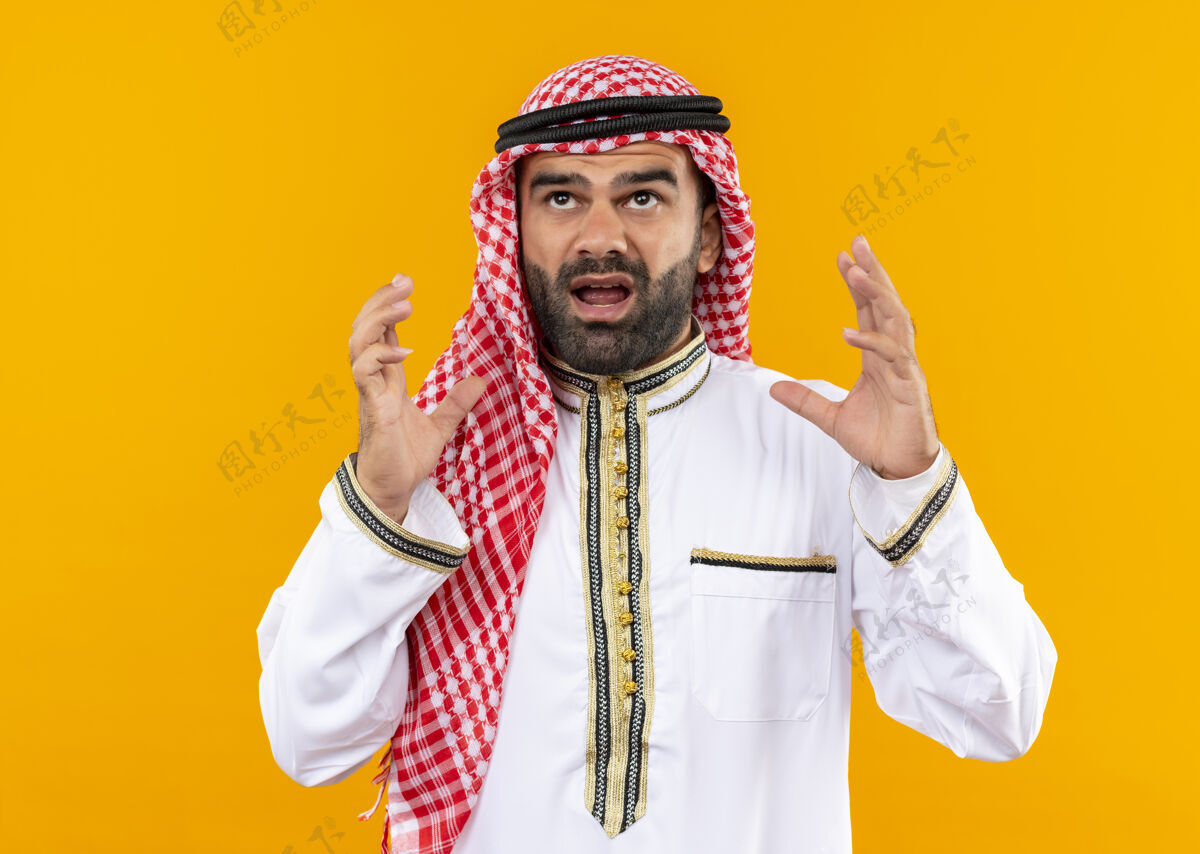 手沮丧的阿拉伯商人穿着传统服装站在橙色的墙上高声喊叫沮丧阿拉伯语穿