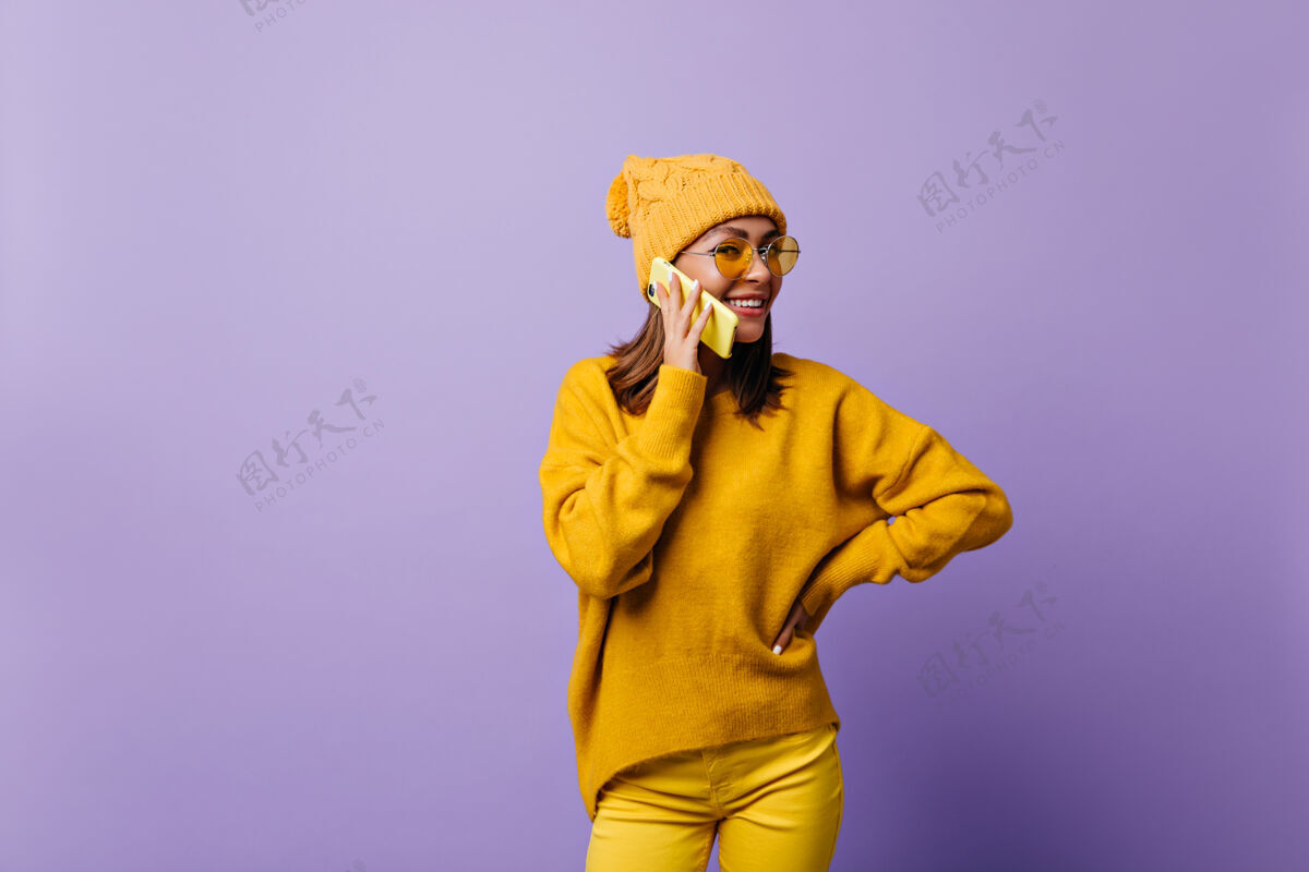 成人女孩喜欢橙色 穿着时髦的服装为新的snapportrait拍照模特在黄色的电话里交谈 友好的微笑奇迹现代黑发