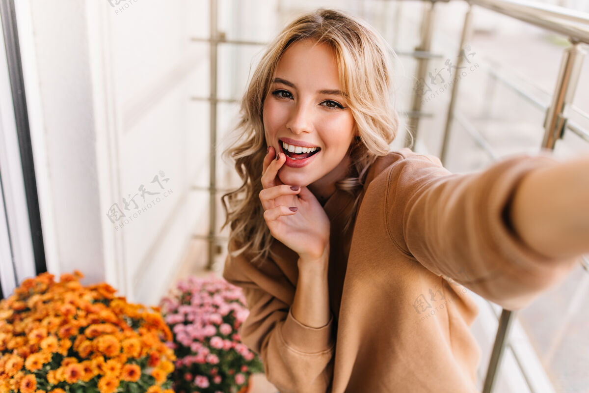 积极风度翩翩的年轻女子在阳台上自拍微笑的梦幻女孩在橘子花边摆姿势的肖像植物情绪观点