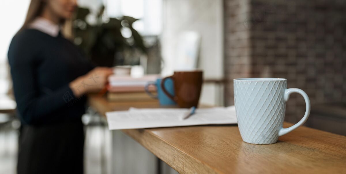 商务台子上的咖啡杯正面图 离焦女士工作杯子会议