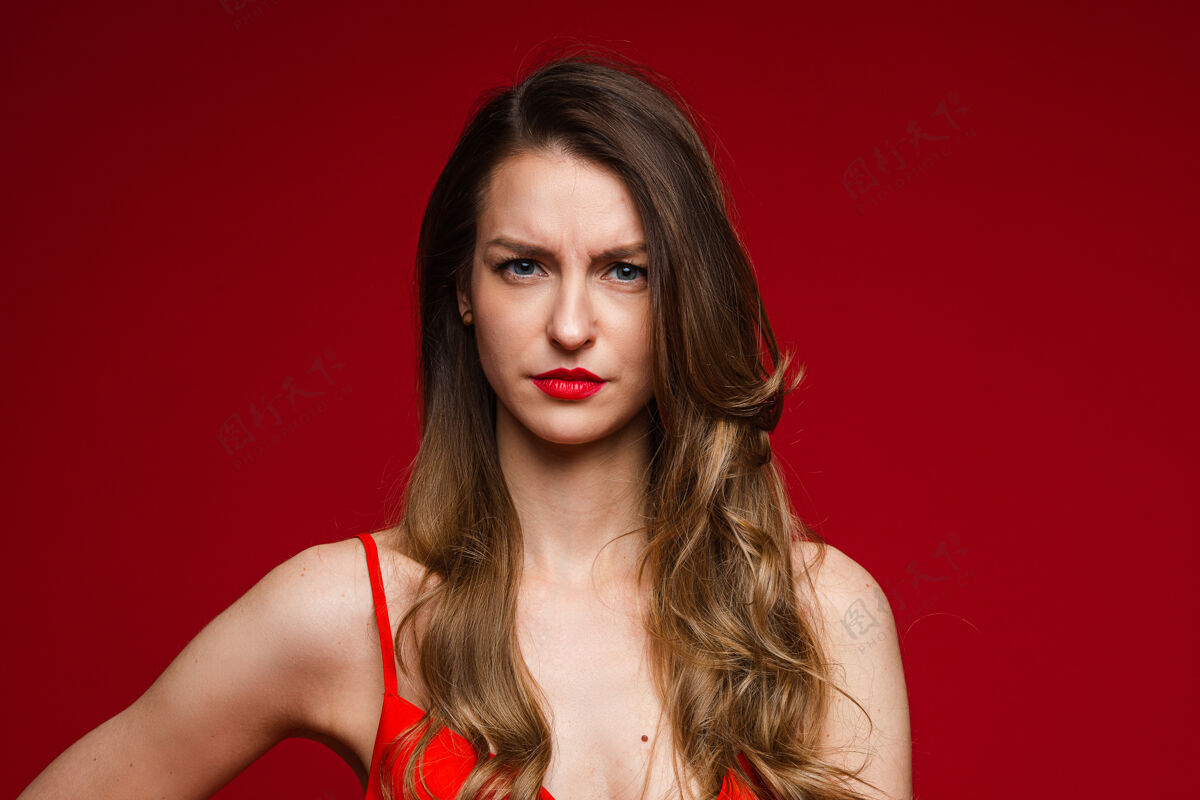 肢体语言年轻人不高兴的头部镜头严肃的女性皱眉在红色工作室背景与广告空间复制完美头晕肩膀