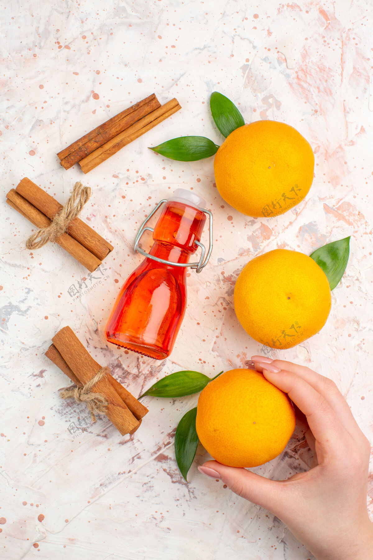 甜橙顶视图新鲜橘子肉桂棒橘子在女性手瓶明亮的表面景观顶部柑橘