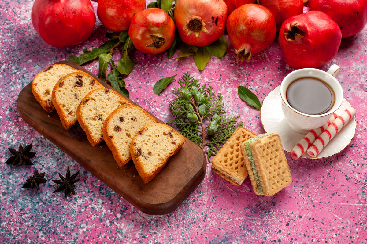 切片在粉红色的桌子上可以看到新鲜的红石榴 切片蛋糕茶和华夫饼果汁新鲜华夫饼
