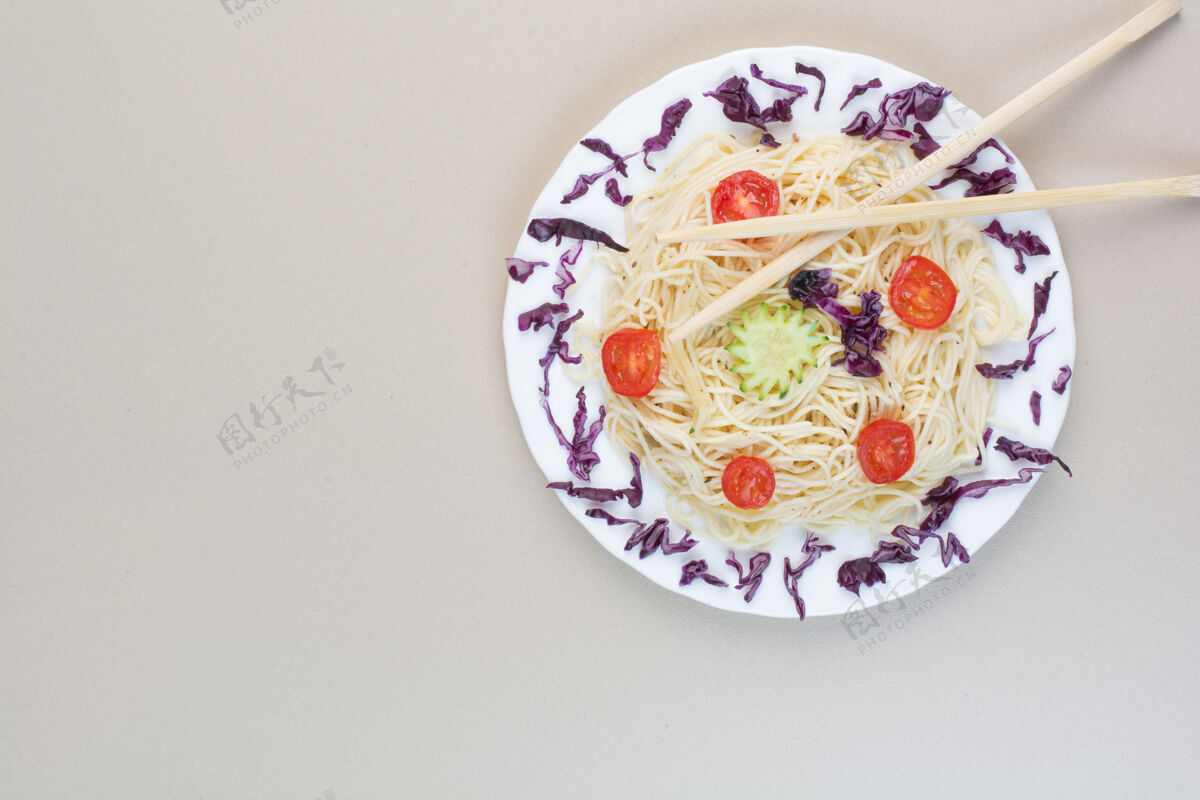 筷子白盘子里放着卷心菜和西红柿片的意大利面卷心菜晚餐切片